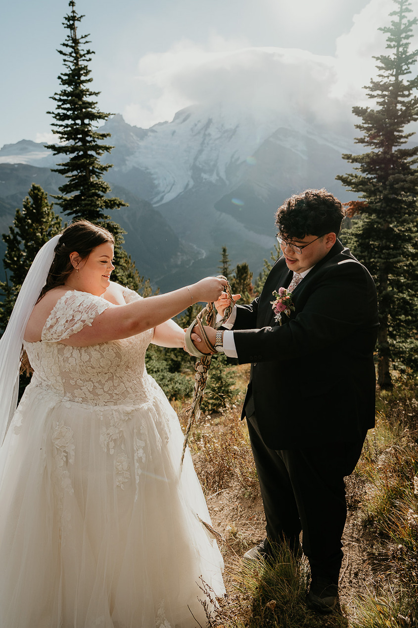 a couple performing a hand fasting ceremony, part of what an elopement ceremony can look like.