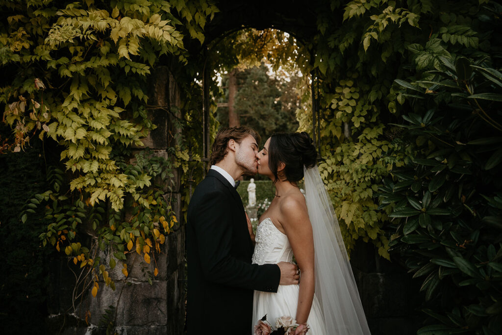 newlyweds kissing under an archway.