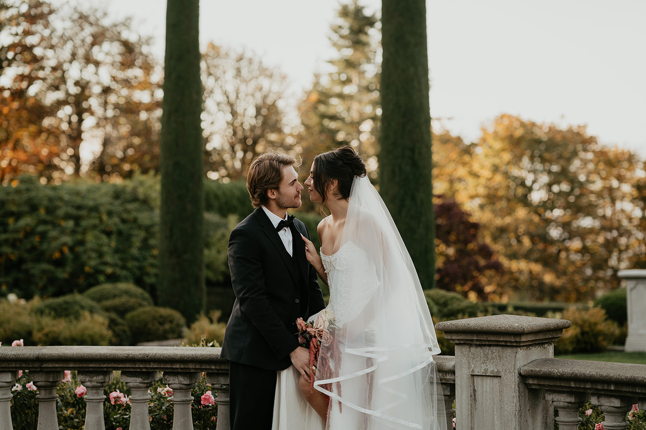 newlyweds holding hands and smiling next to each other while standing in a courtyard during their Chateau de Michellia Wedding.