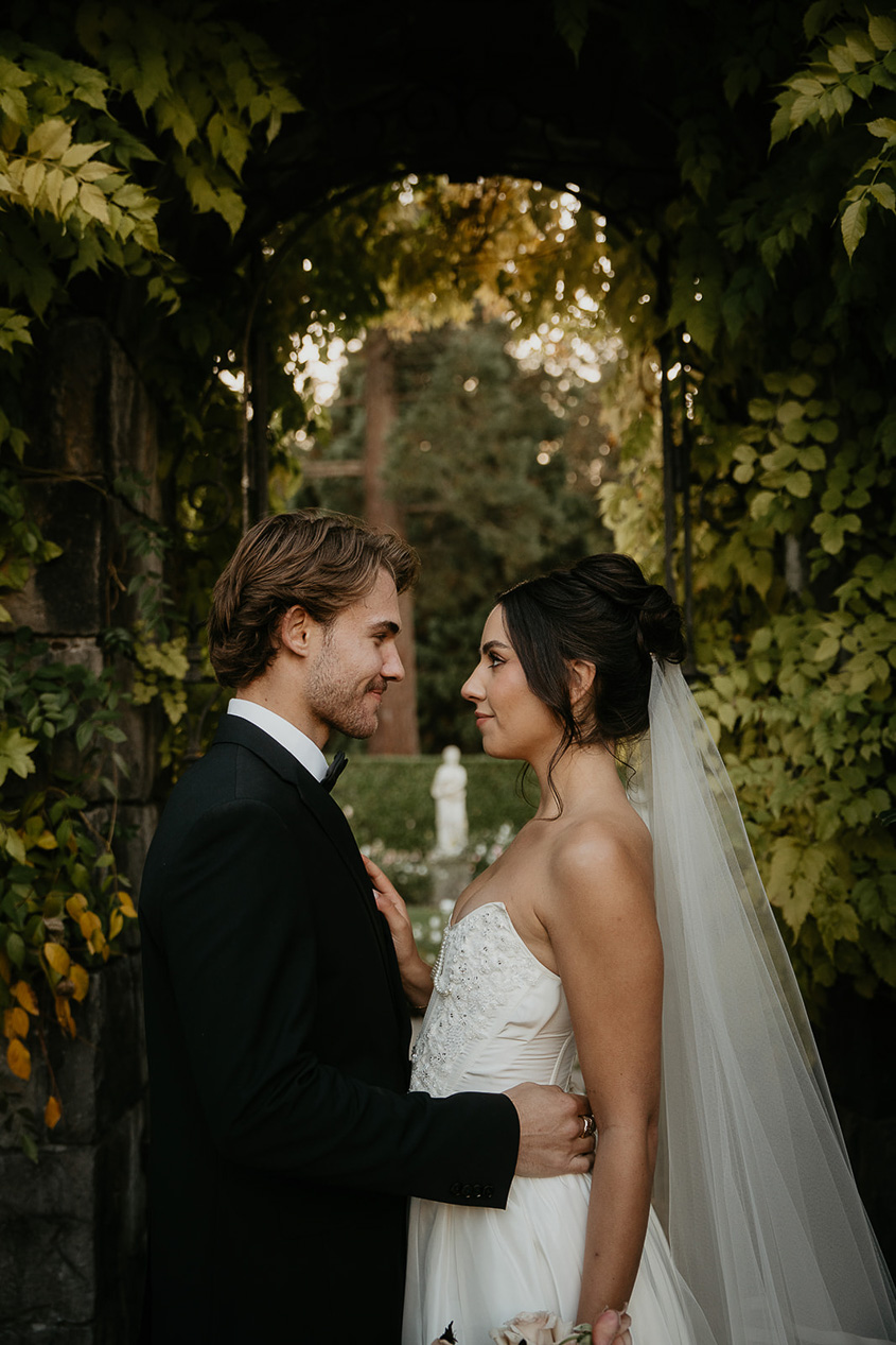 newlyweds looking lovingly into each other's eyes while under an archway.