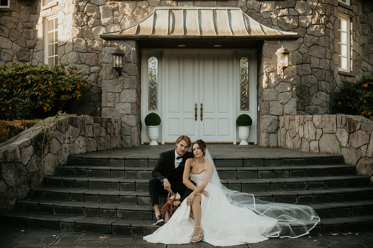 a couple sitting on the steps in front of two white doors.