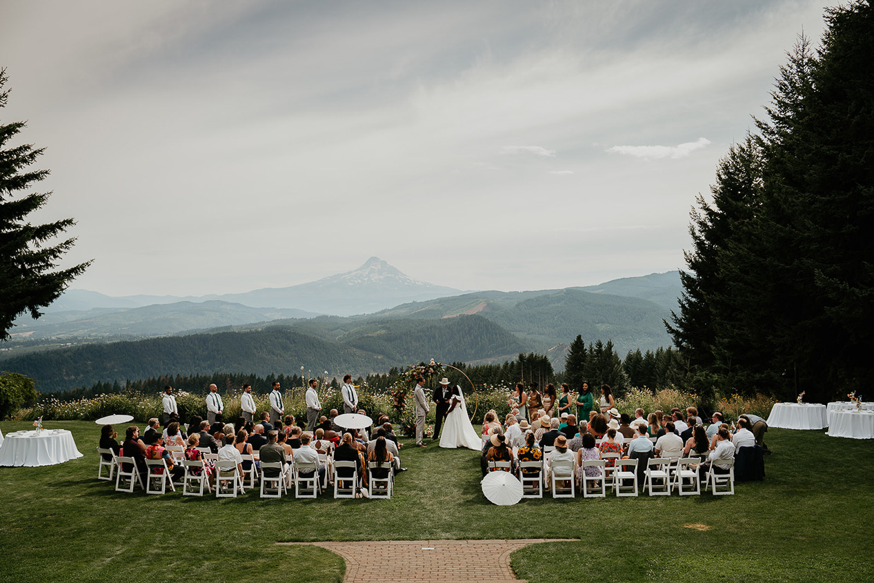 newlyweds getting married on a lawn with mountain views in the background at George Crest Vineyards, one of the best columbia river gorge wedding venues.