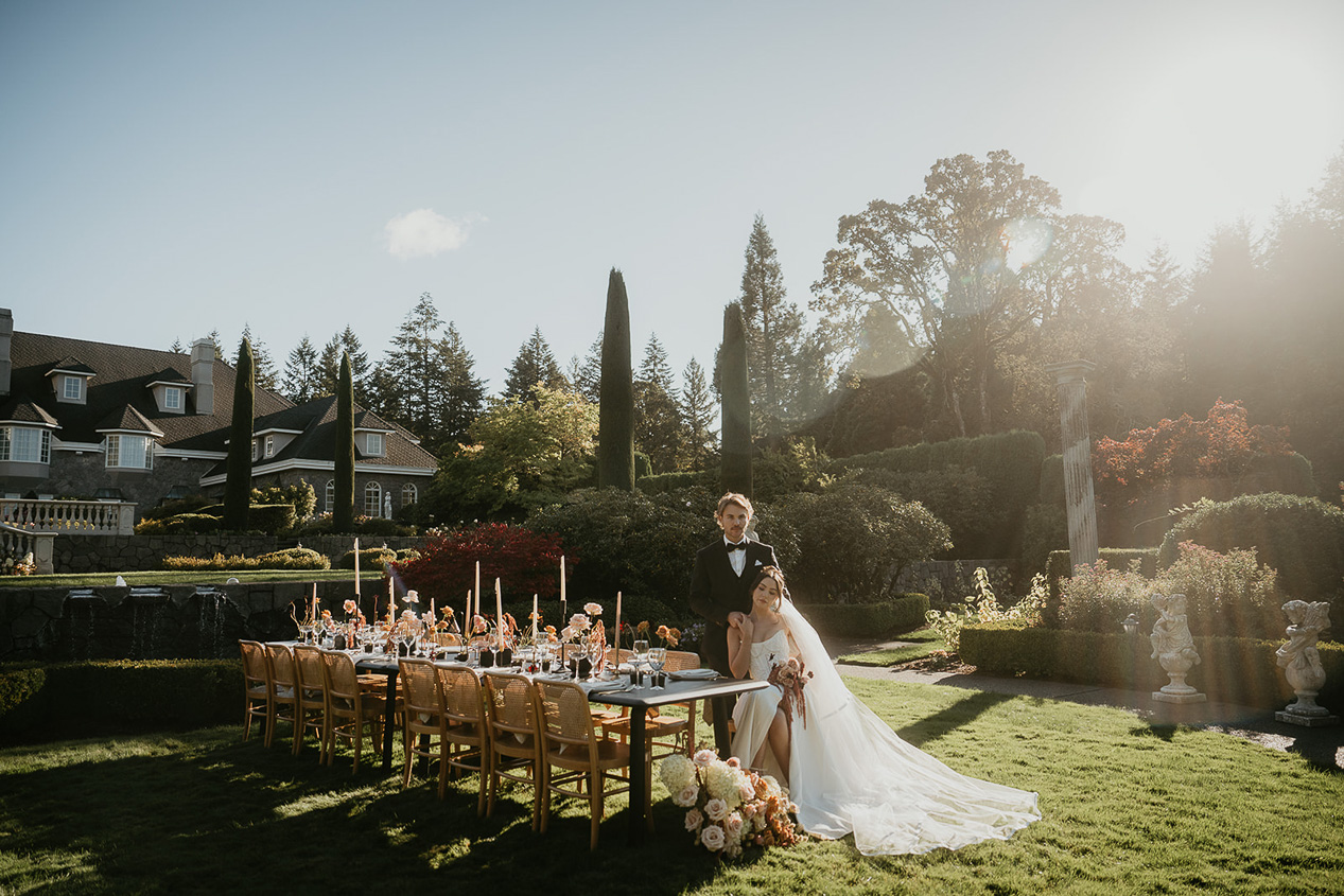 newlyweds by a large dining on a grassy lawn at the Chateau de Michellia.