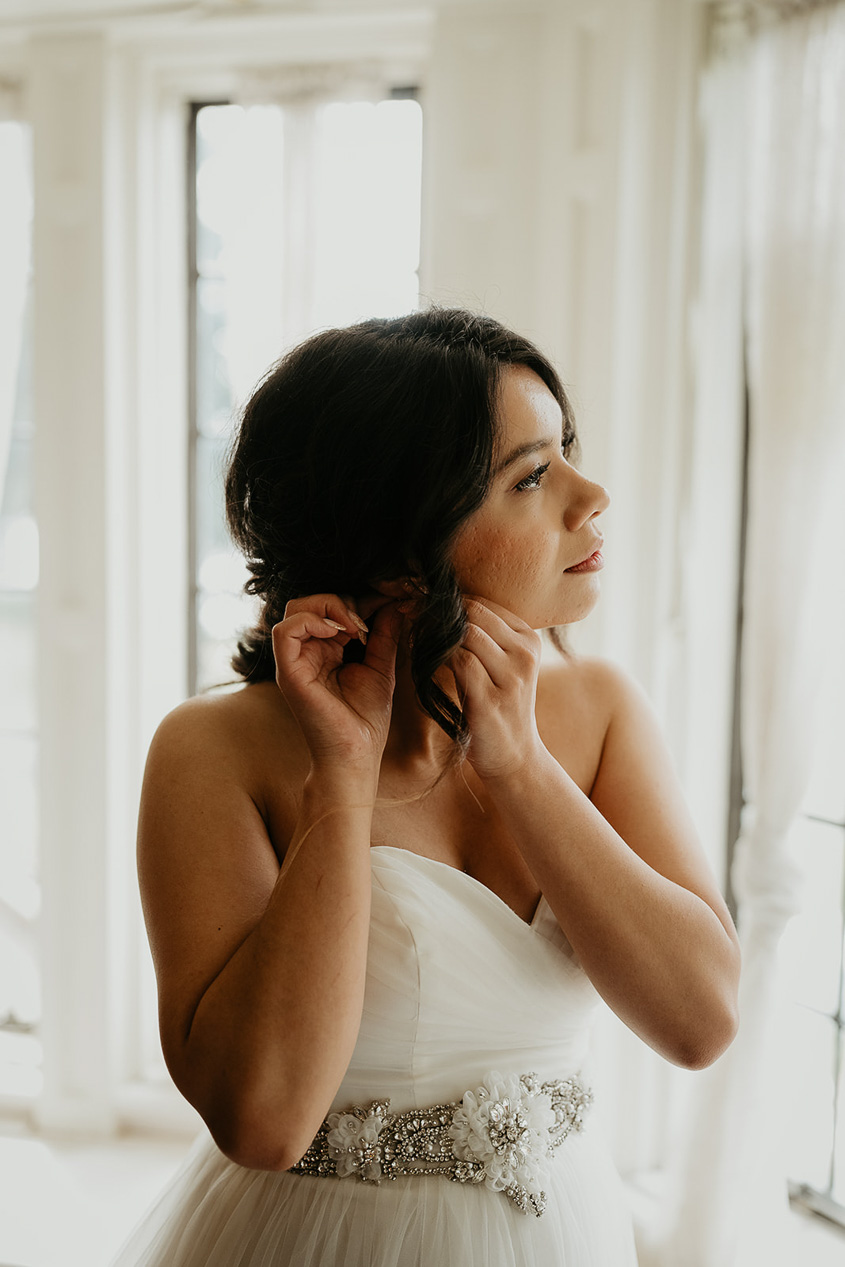 the bride putting on an earring.