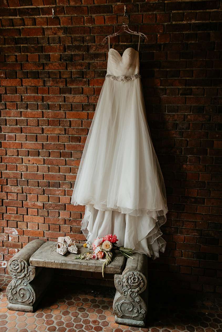 a wedding dress hanging on a brick wall during a thornewood castle wedding.