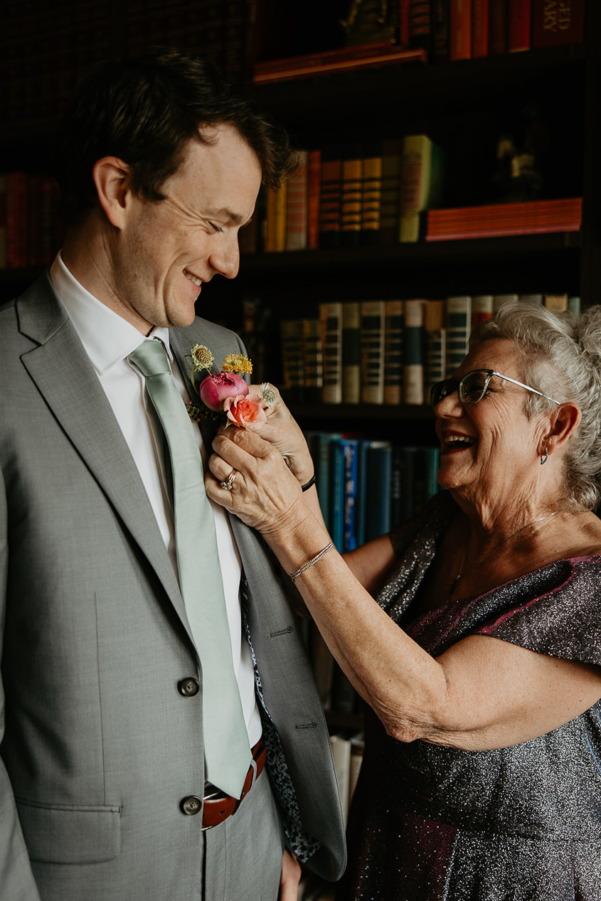 the groom getting a flower attached to his lapel.