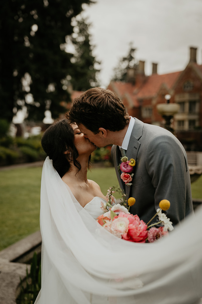 the bride and groom kissing as the bride's veil sways in the wind.
