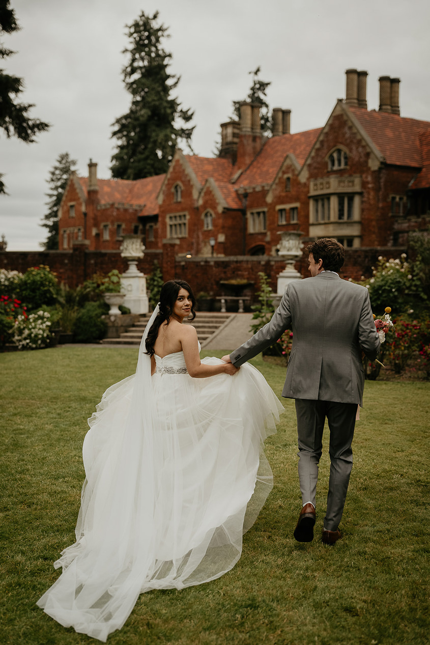 newlyweds walking on the lawn of the thornewood castle during their wedding