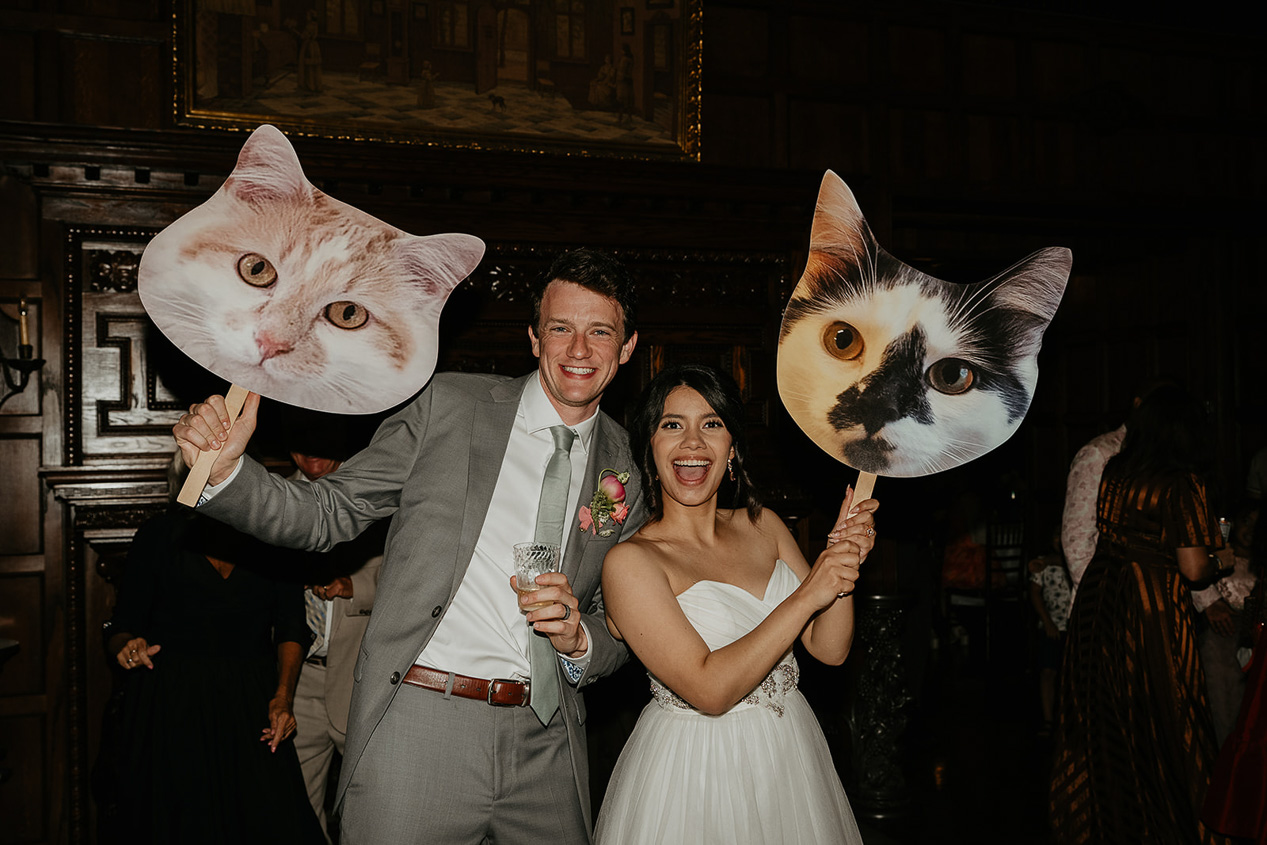 newlyweds holding giant cutouts of their cats during their thornewood castle wedding.