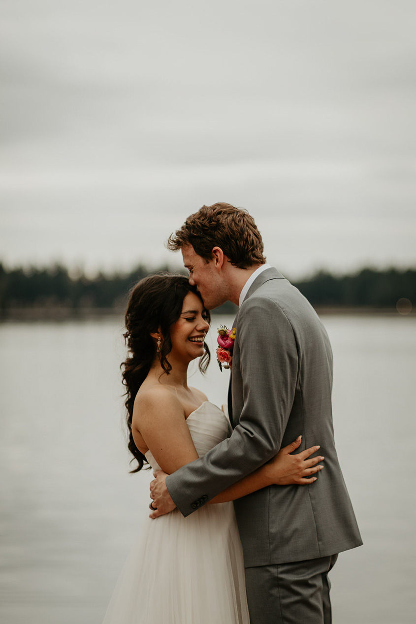 newlyweds hugging with a lake in the background during their thornewood castle wedding.