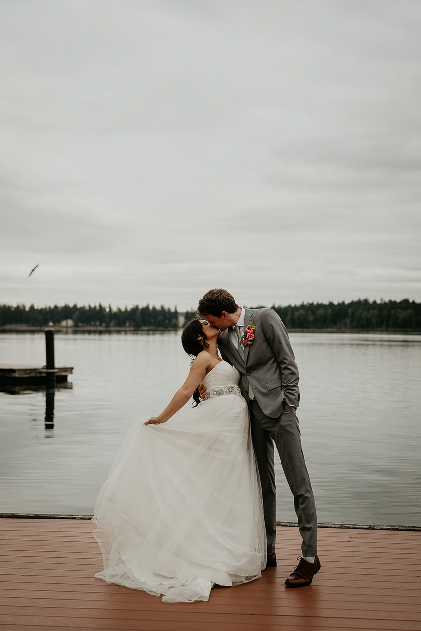 newlyweds kissing on a dock during their thornewood castle wedding.