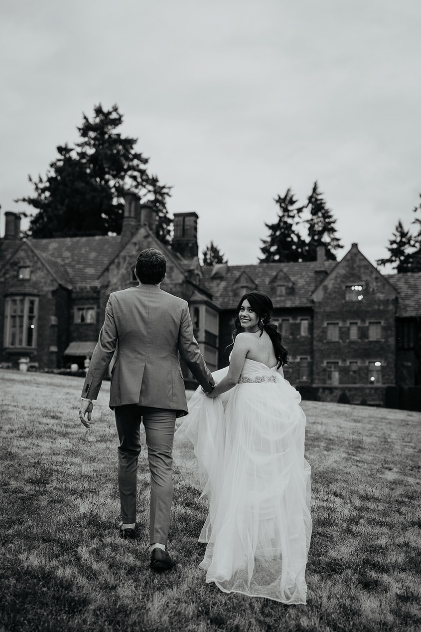 newlyweds walking on the lawn outside the thornewood castle during their wedding