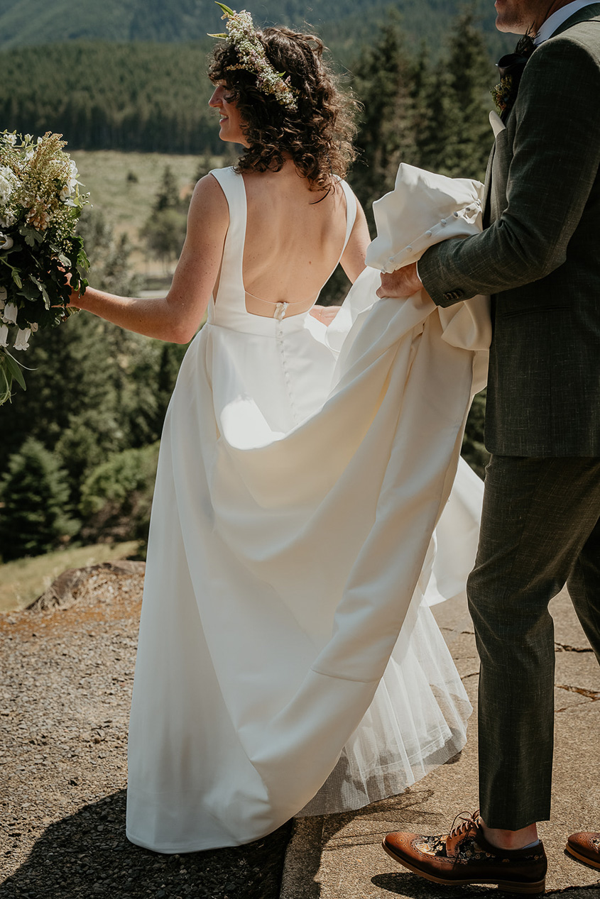 the groom helping keep his bride's dress from dragging on the concrete.