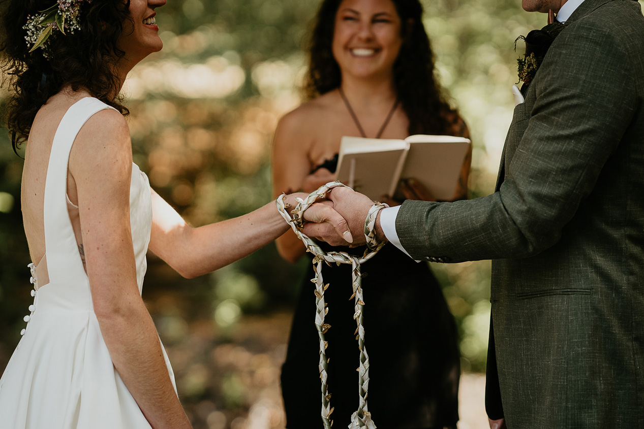 the newlyweds performing a handfasting ceremony during their rustic barn wedding.