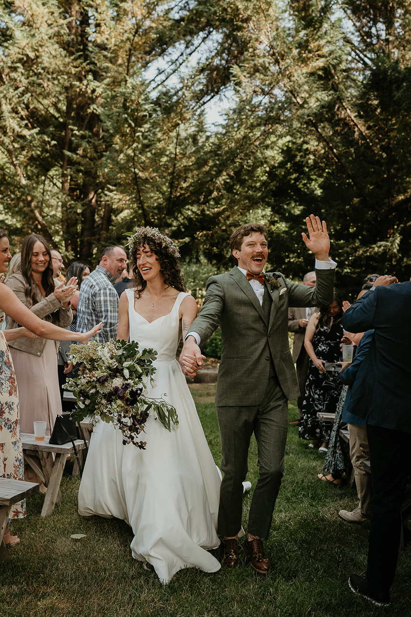 the newlyweds walking down the aisle after their ceremony, with the friends and family cheering them on.