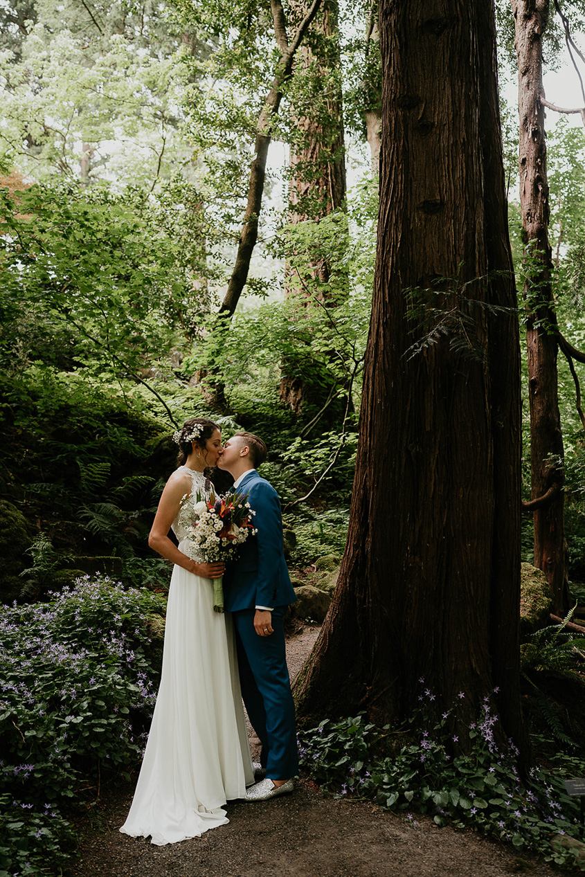 newlyweds kissing under a tree at Leach Botanical Garden, one of the best wedding venues in Portland.