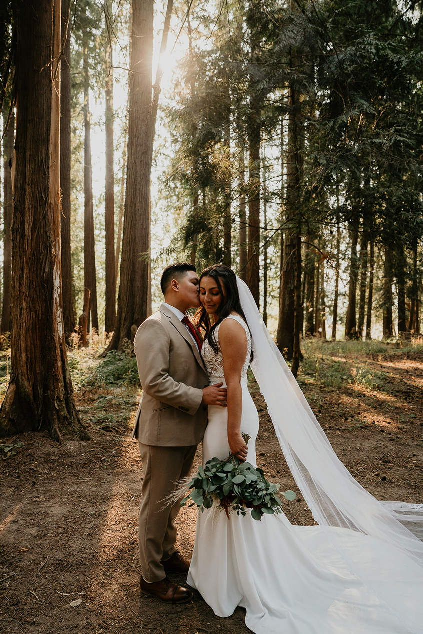 newlyweds kissing among the trees at CedarVale Events, one of the best wedding venues at Portland.