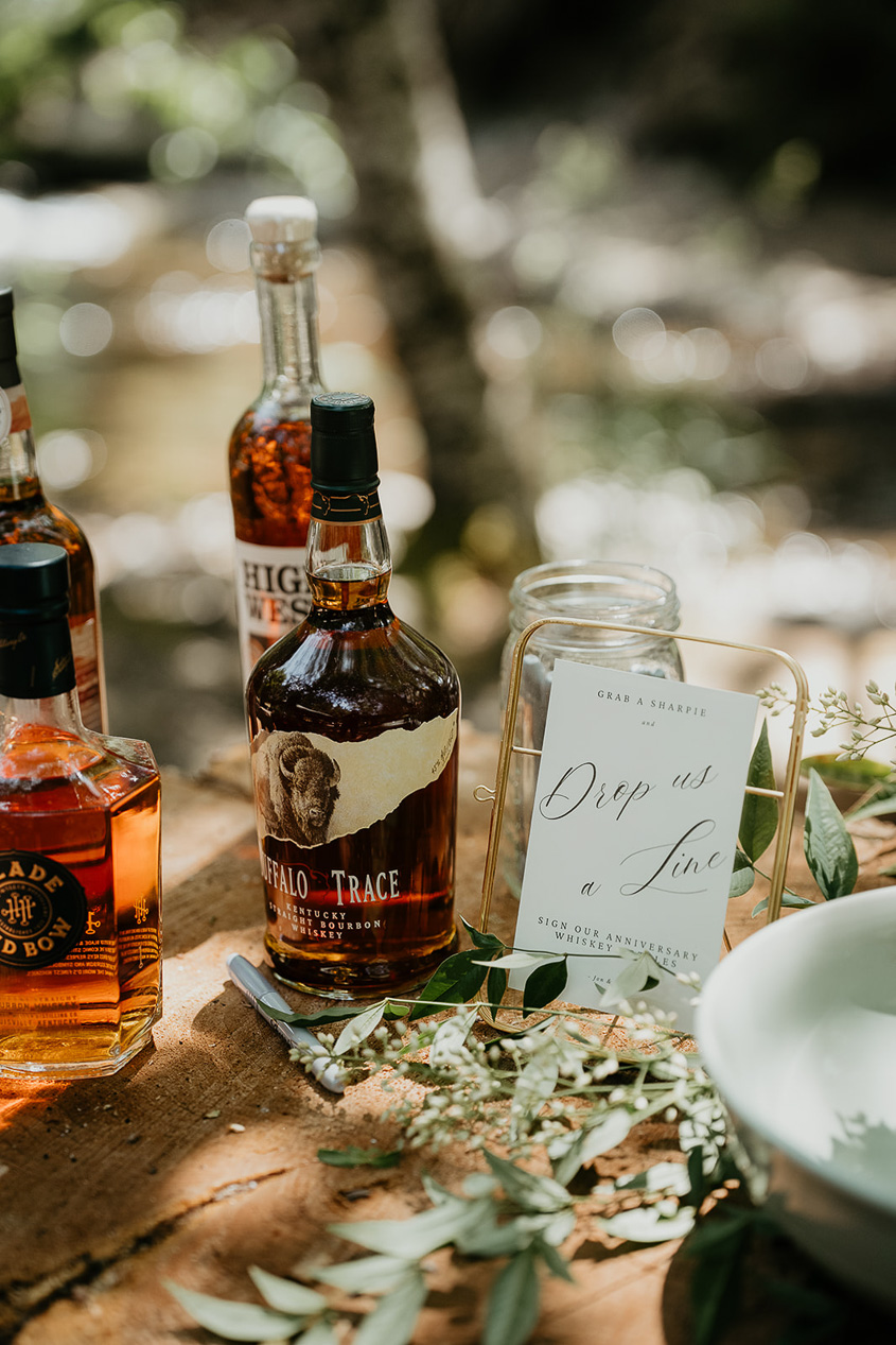 whiskey bottles and a sign that informs guests to sign their anniversary whiskey.