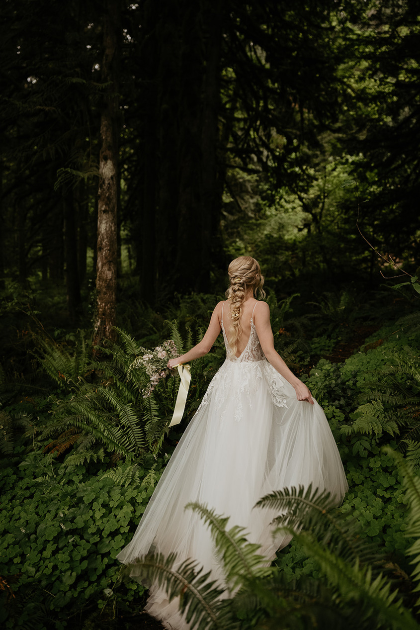a bride walking into the forest at the Highland Farms wedding venue.