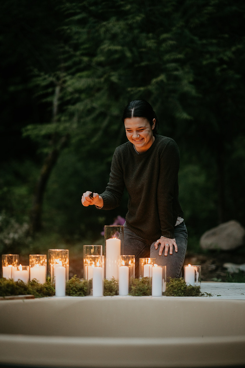 a wedding planner lighting candles next to a hot tub at the Highland Farms wedding venue.