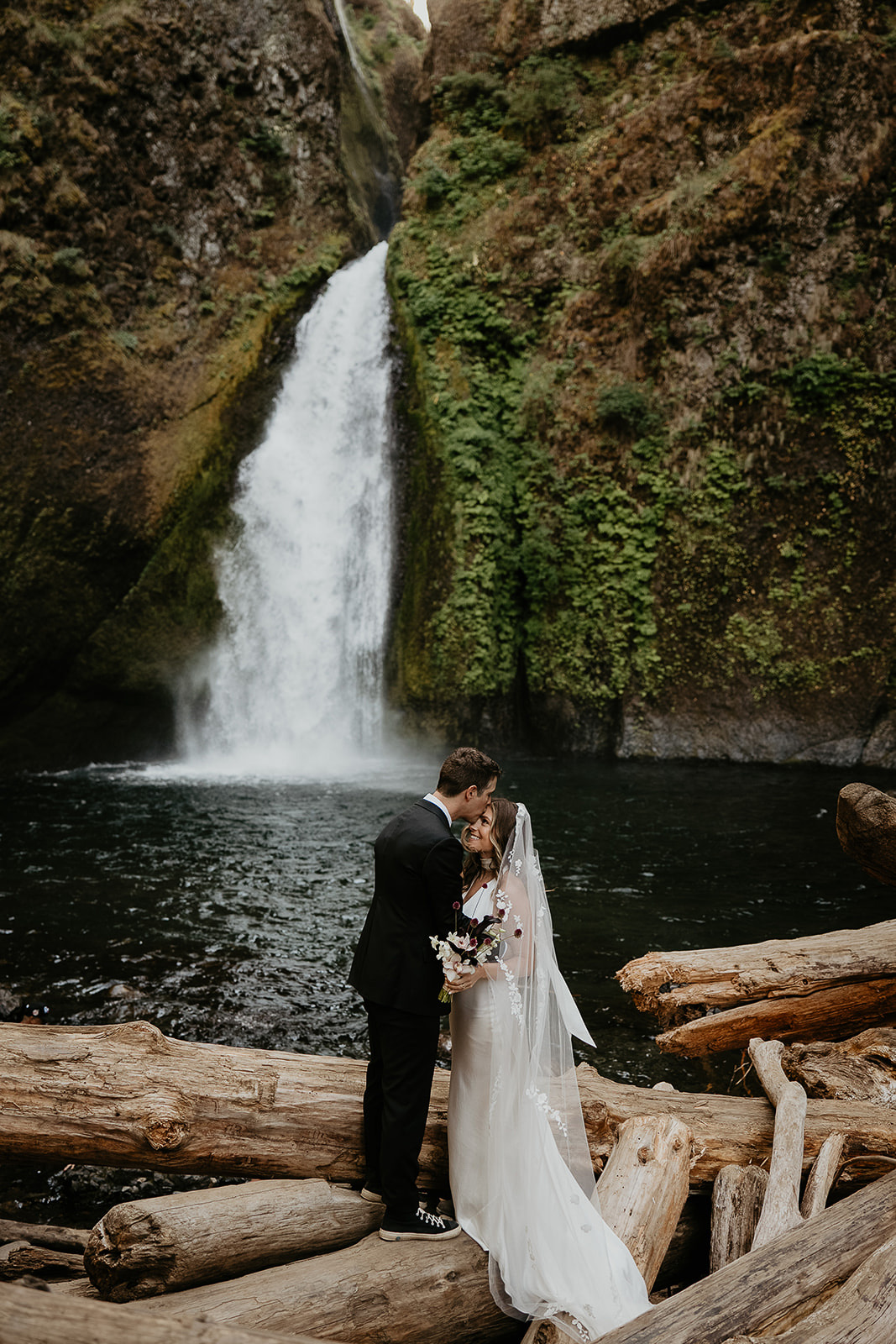 newlyweds kissing in front of a waterfall, which they included as part of their plan for their micro wedding.