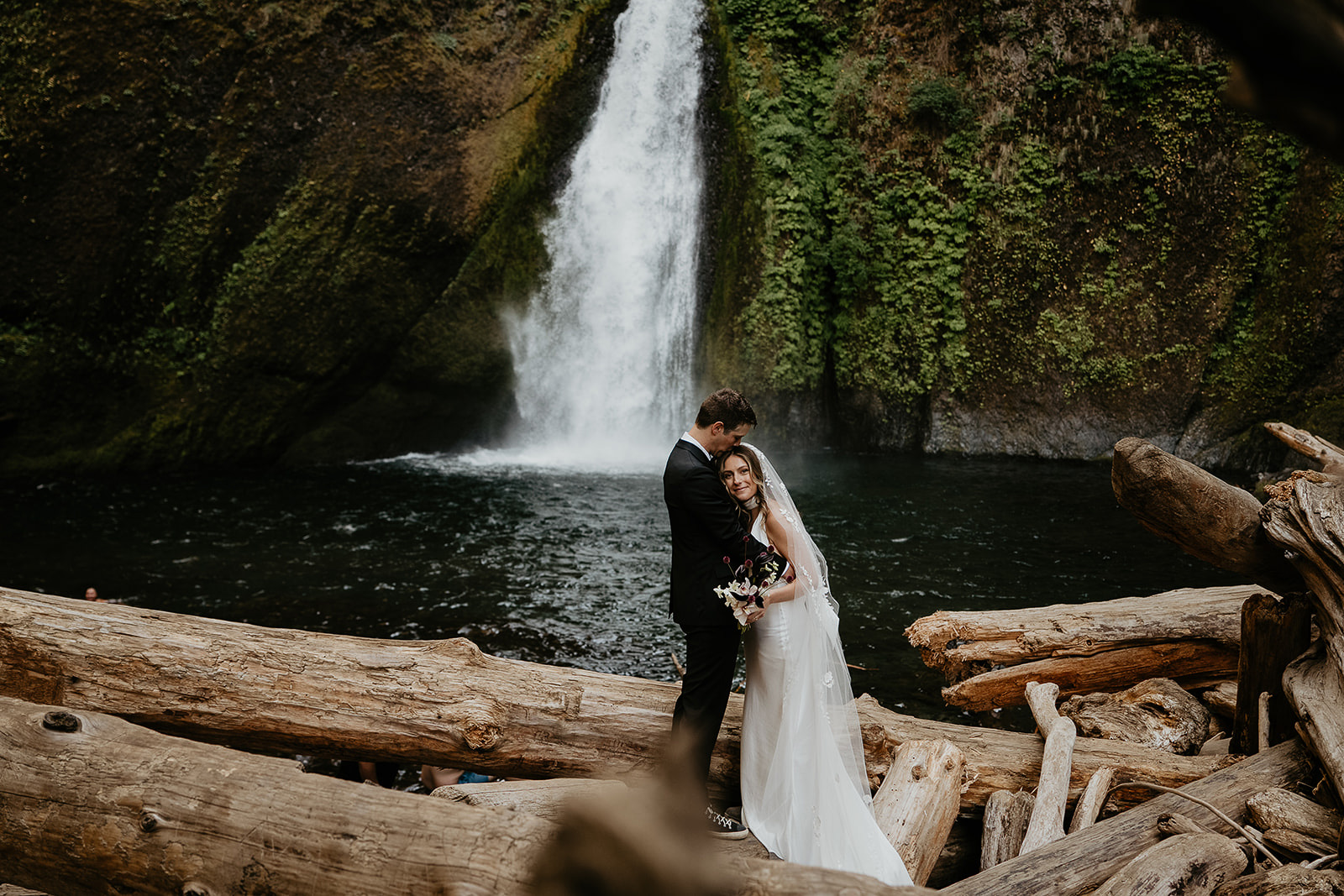 newlyweds in front of a waterfall, which they included as part of their plan for their micro wedding.