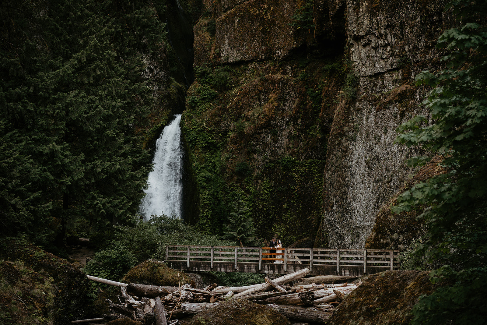 newlyweds on a bridge by a waterfall, which they included as part of their plan for their micro wedding.