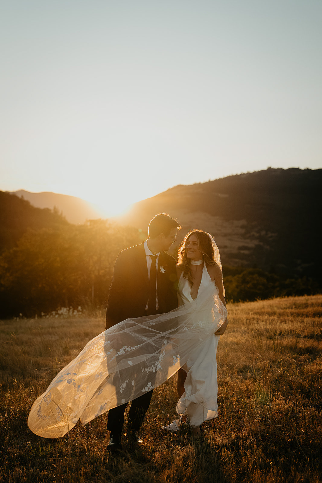 newlyweds walking in a field at sunset, which they included as part of their plan for their micro wedding.