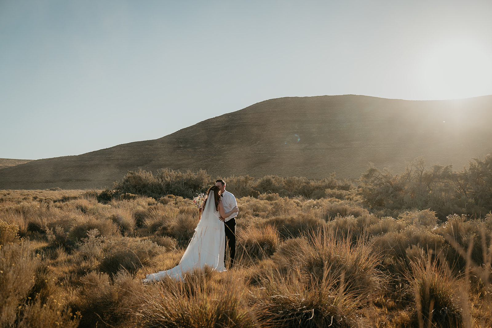 newlyweds kissing among desert bushes during their Alvord Desert, Oregon elopement.