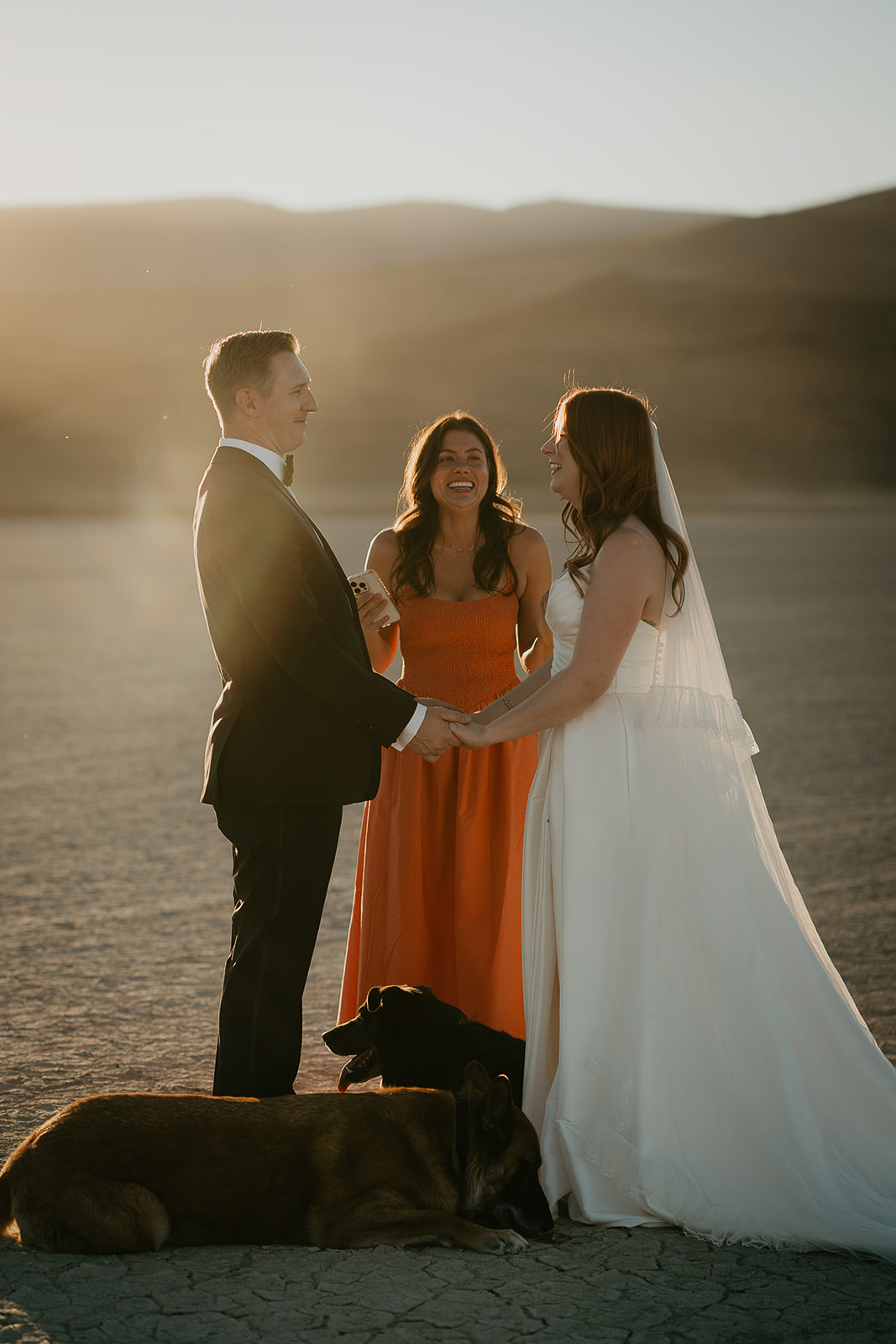 newlyweds holding hands as their officiant shares a message during their Alvord Desert, Oregon elopement.