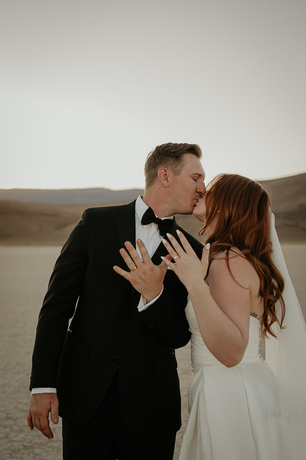 newlyweds kissing and showing off their wedding rings.