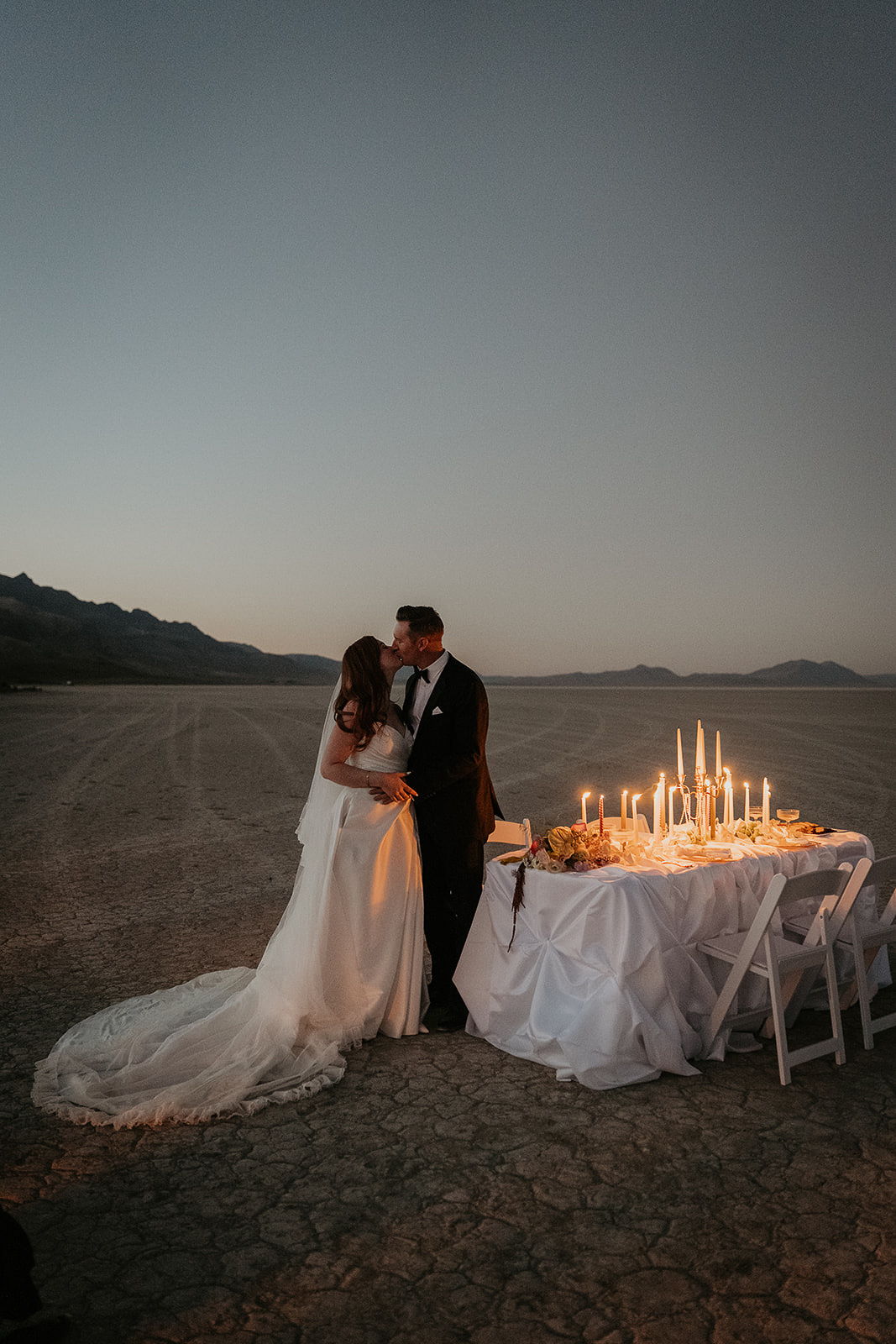 newlyweds kissing next to their decorated table in the desert during their Alvord Desert, Oregon elopement.