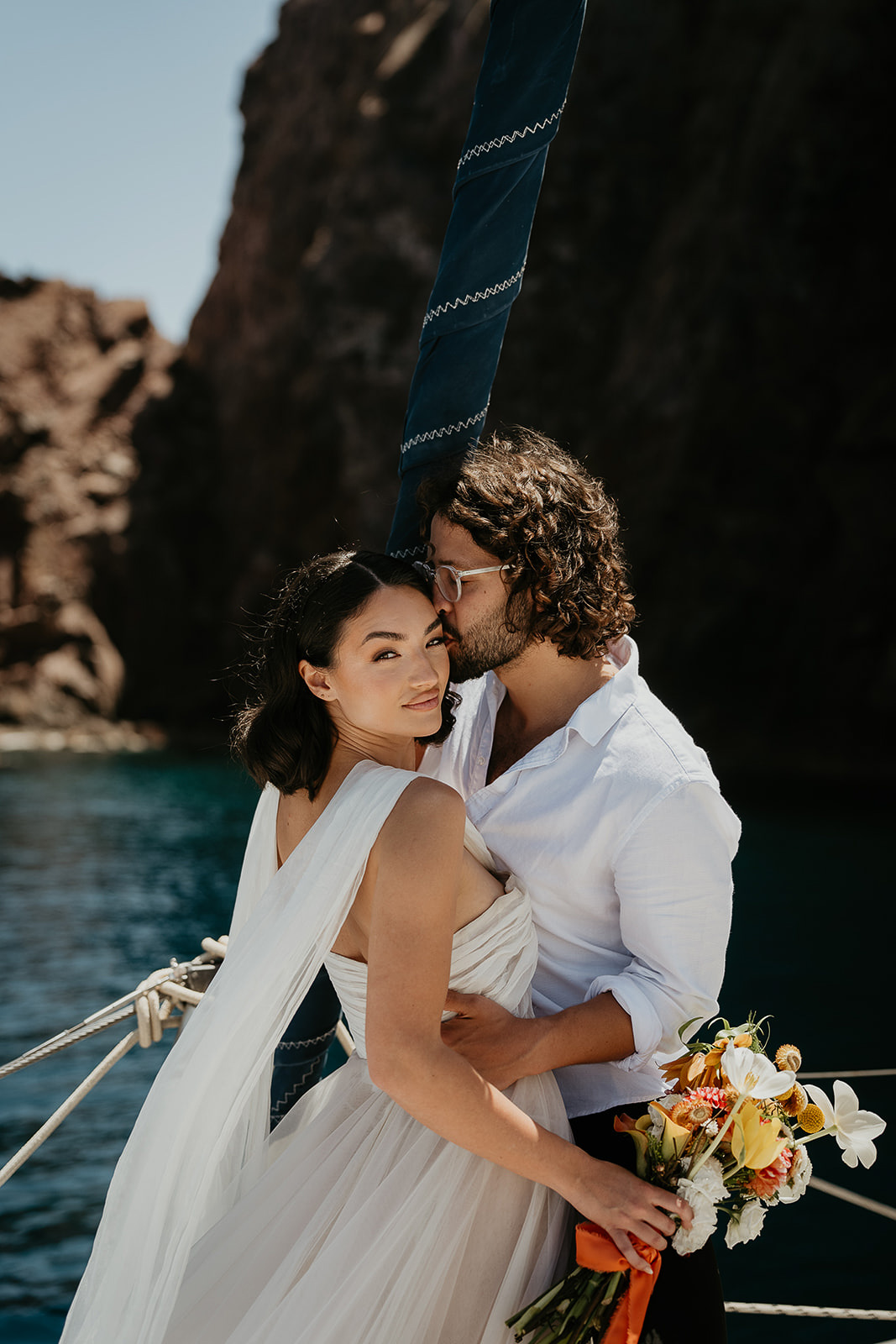 a couple kissing on a sailboat in milos as part as they elope in Greece.
