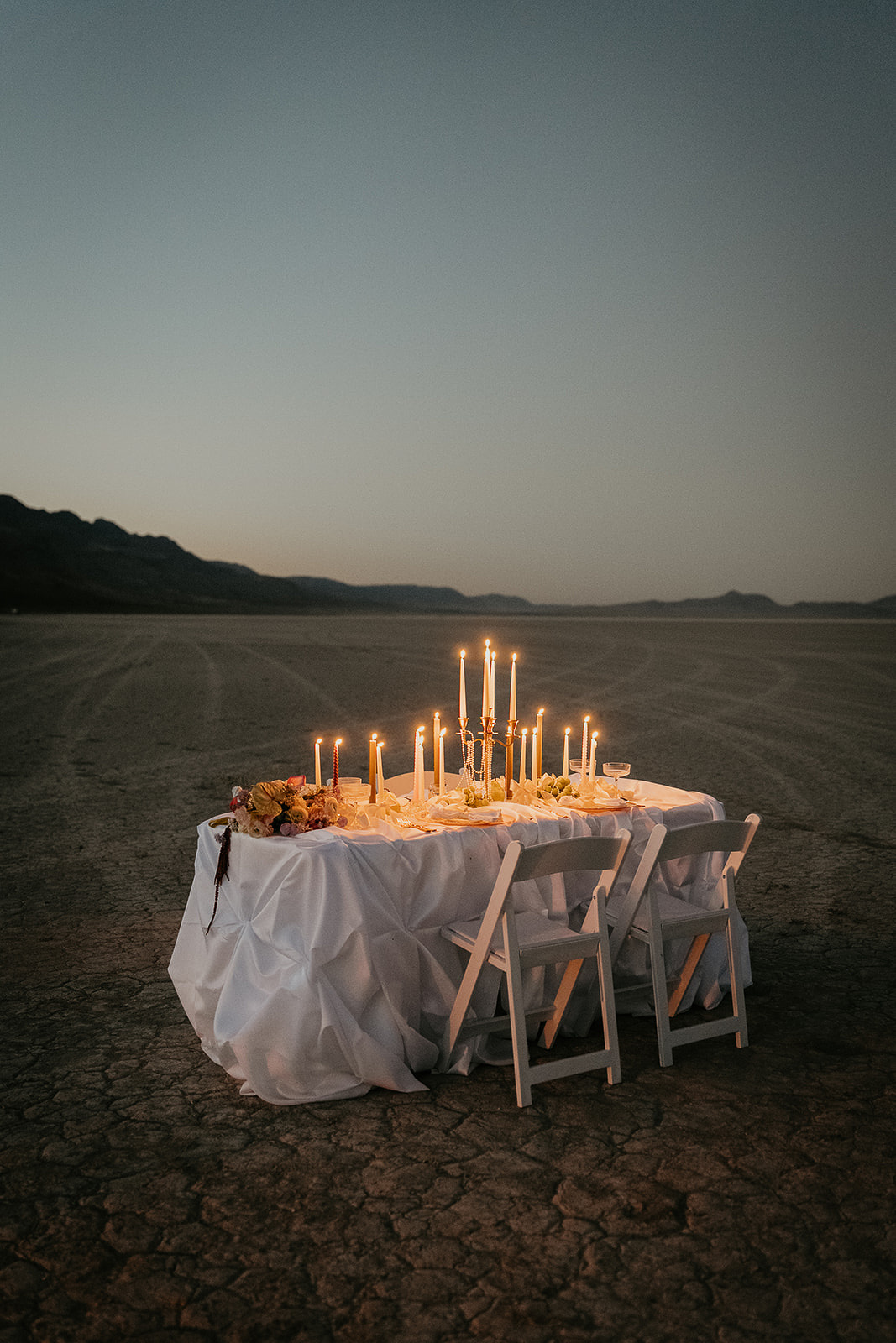 a decorated table with candles, pearls, and snacks in the desert.