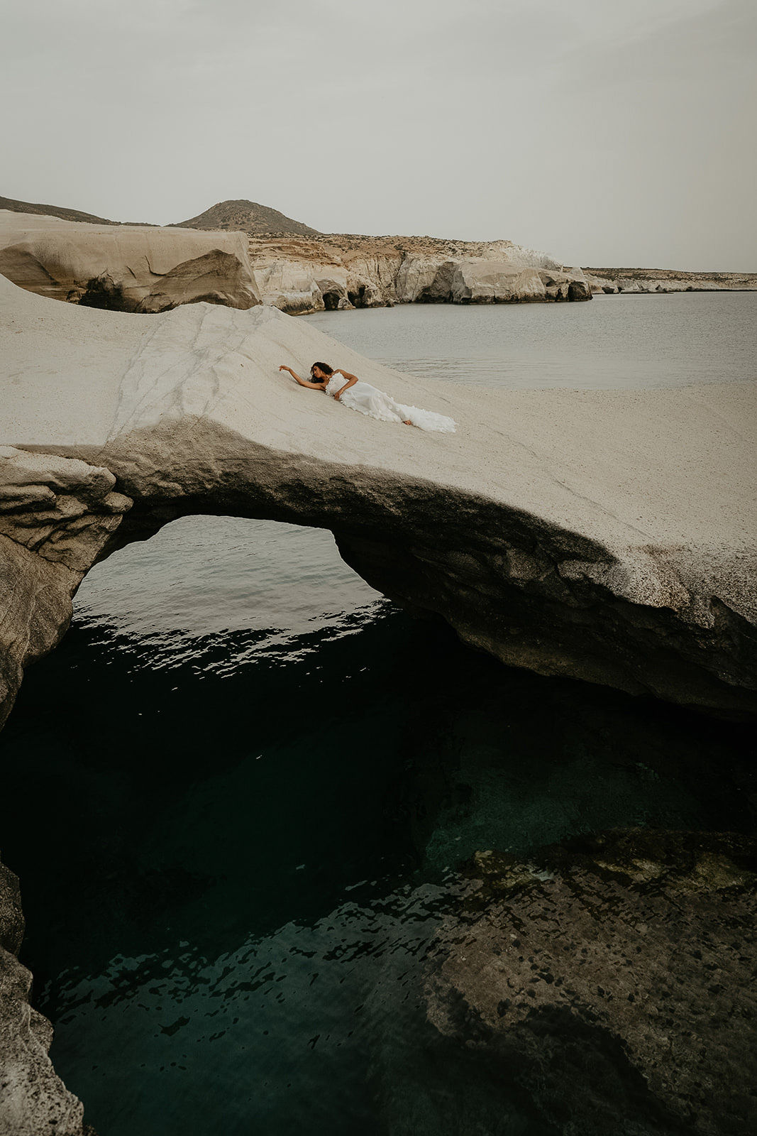 a bride laying on an archway over the ocean.