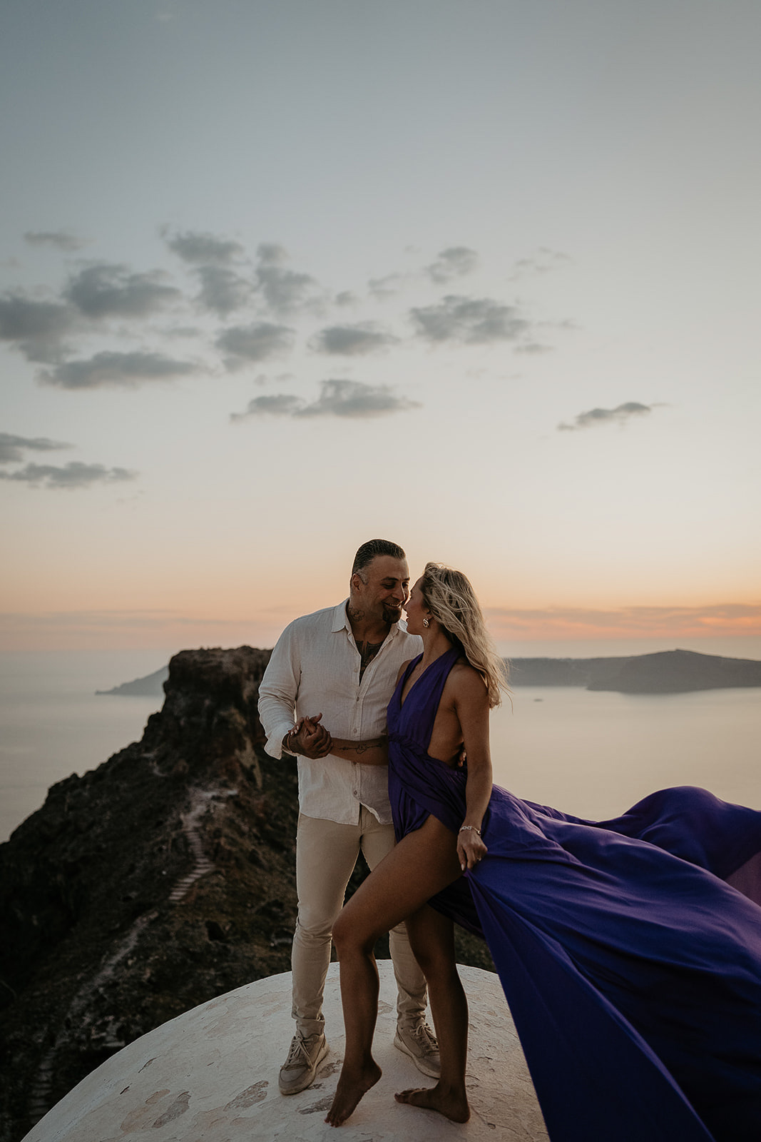 a couple overlooking the ocean at sunset as they elope in greece.