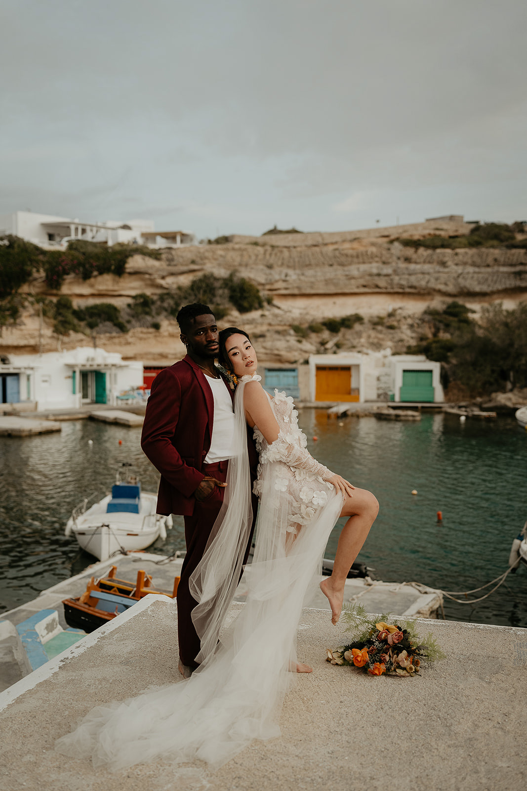 newlyweds posing in front of seaside buildings as they elope in Greece