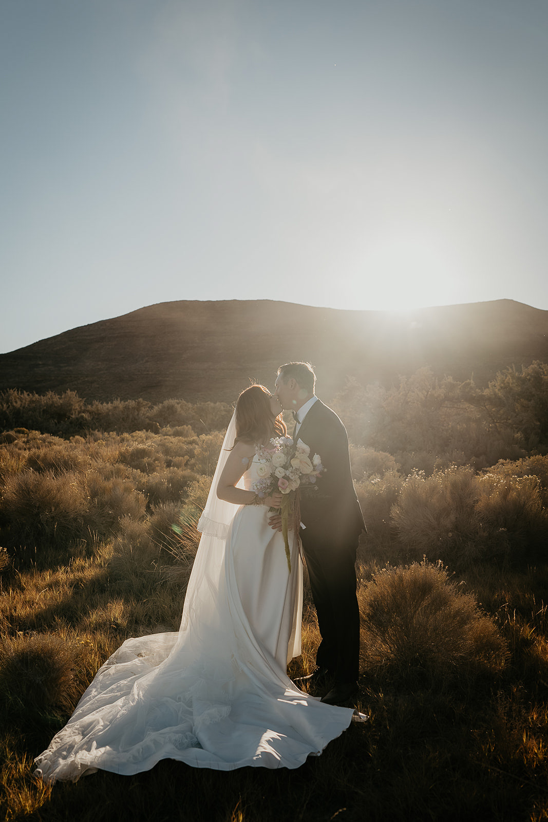 newlyweds kissing among the desert brush during their Alvord Desert, Oregon elopement.
