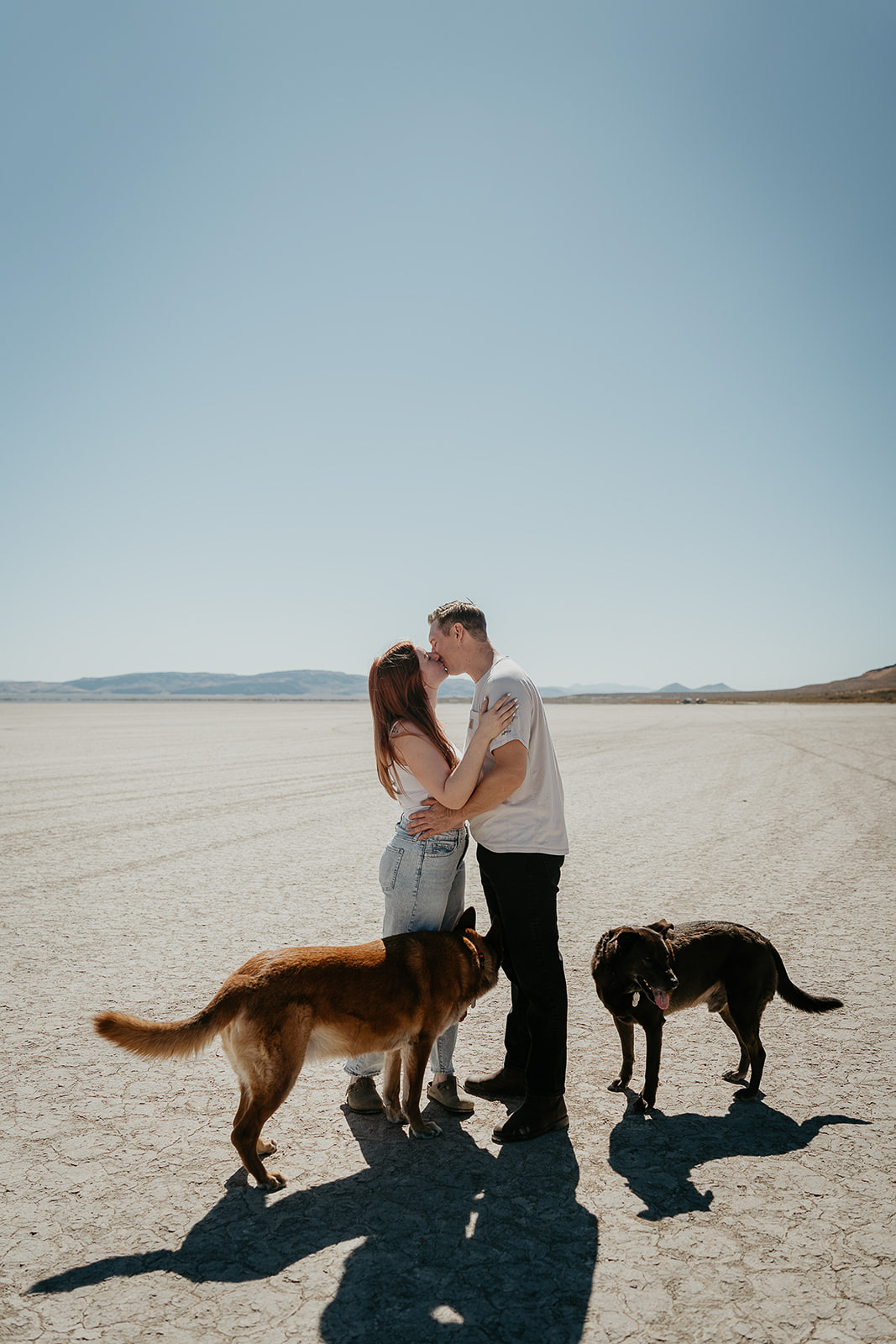 newlyweds kissing with their dogs by their side during their Alvord Desert, Oregon elopement.