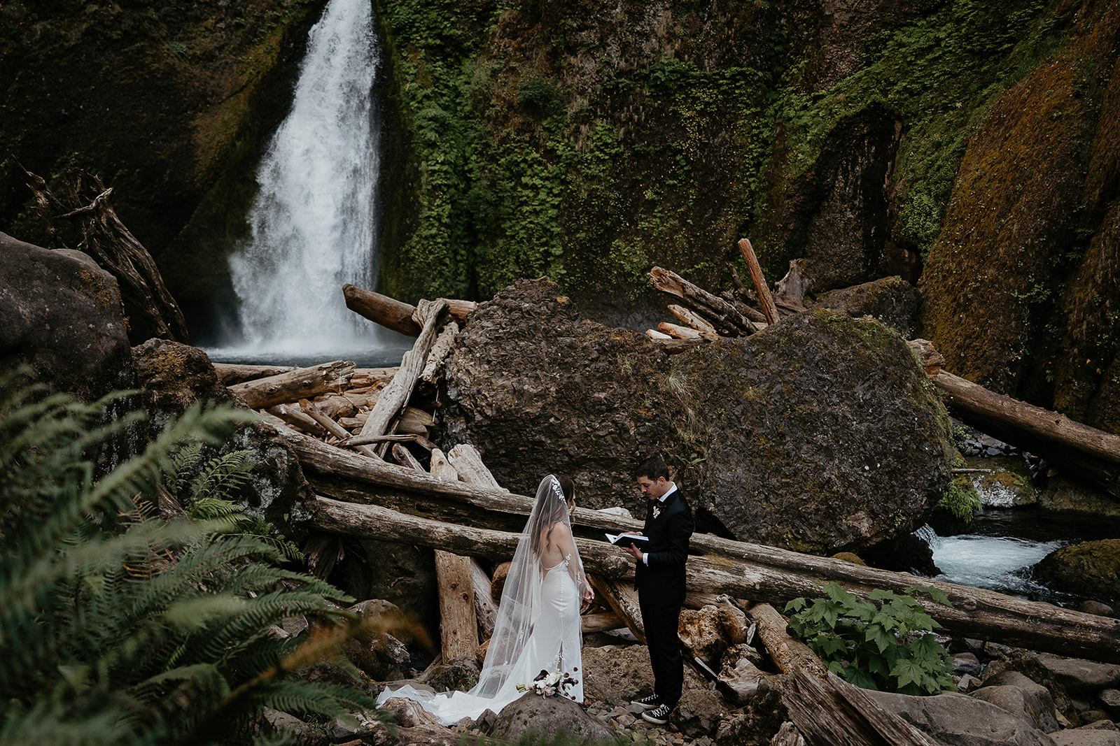 the groom sharing vows by a waterfall during their elopement.