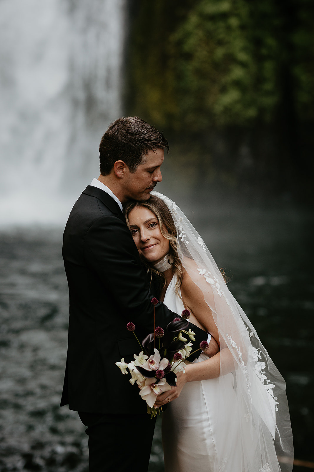 newlyweds hugging by a waterfall during their elopement.