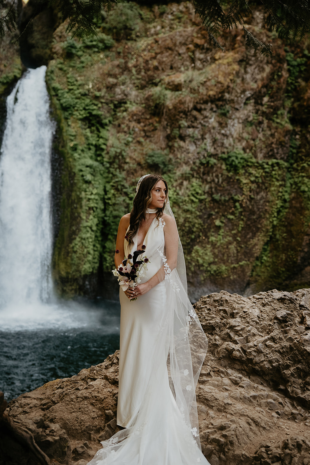the bride posing by a waterfall during her elopement.