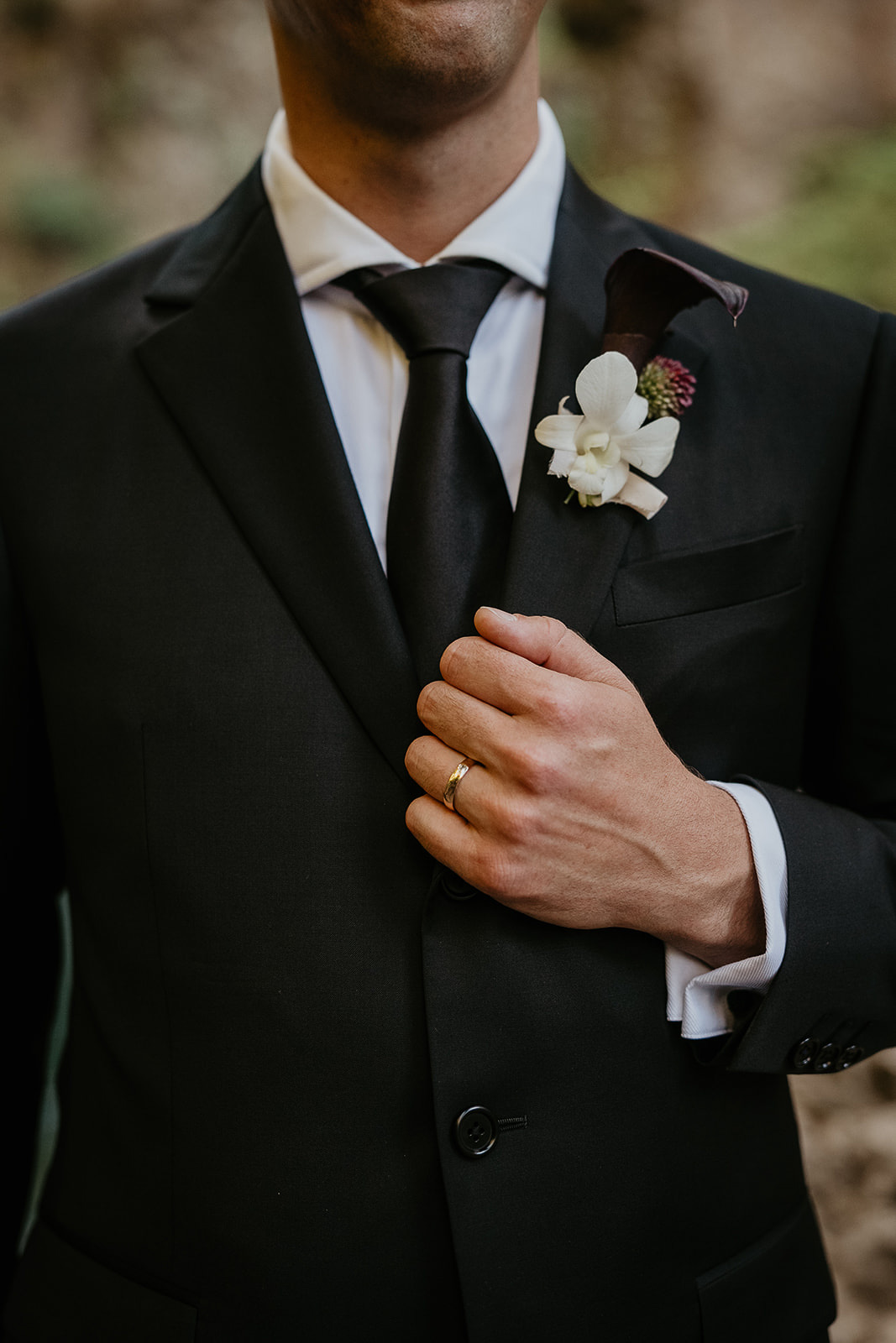 the groom holding is suit jacket, showing off his lapel.