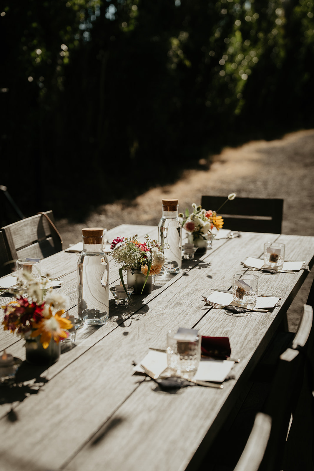 dinner table with flowers, plates, and water carafes.