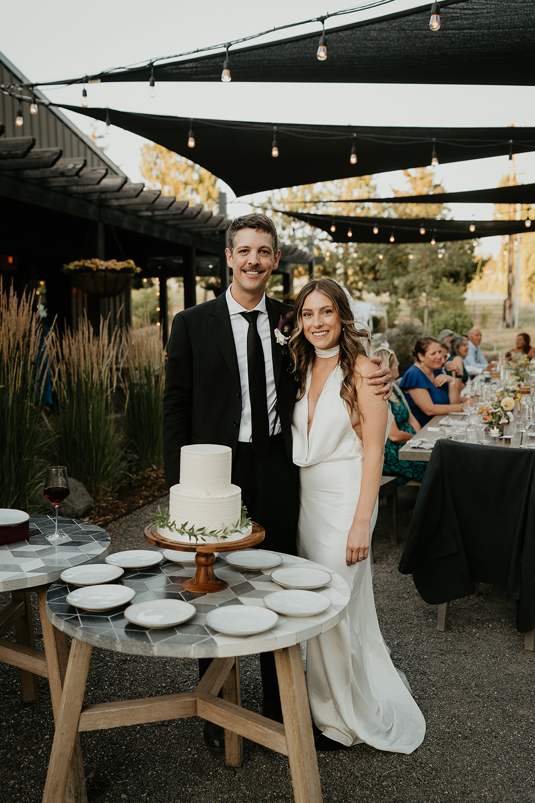 newlyweds smiling by their wedding cake.