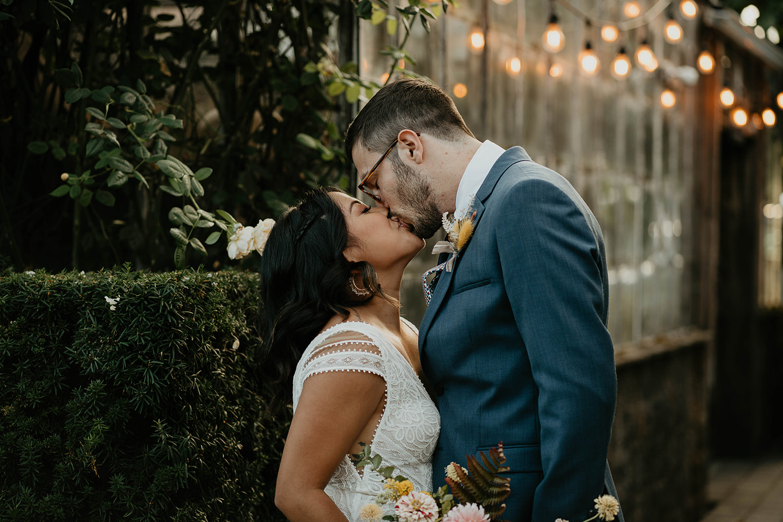 newlyweds kissing by a greenhouse next to the Blockhouse wedding venue. 