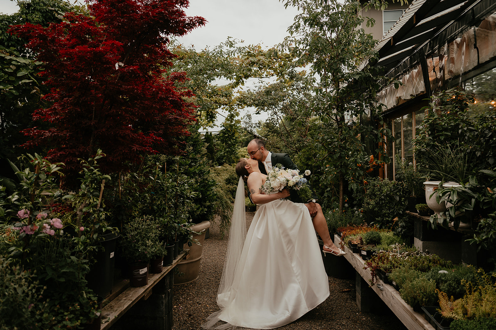 newlyweds kissing in a nursery by the Blockhouse wedding venue. 
