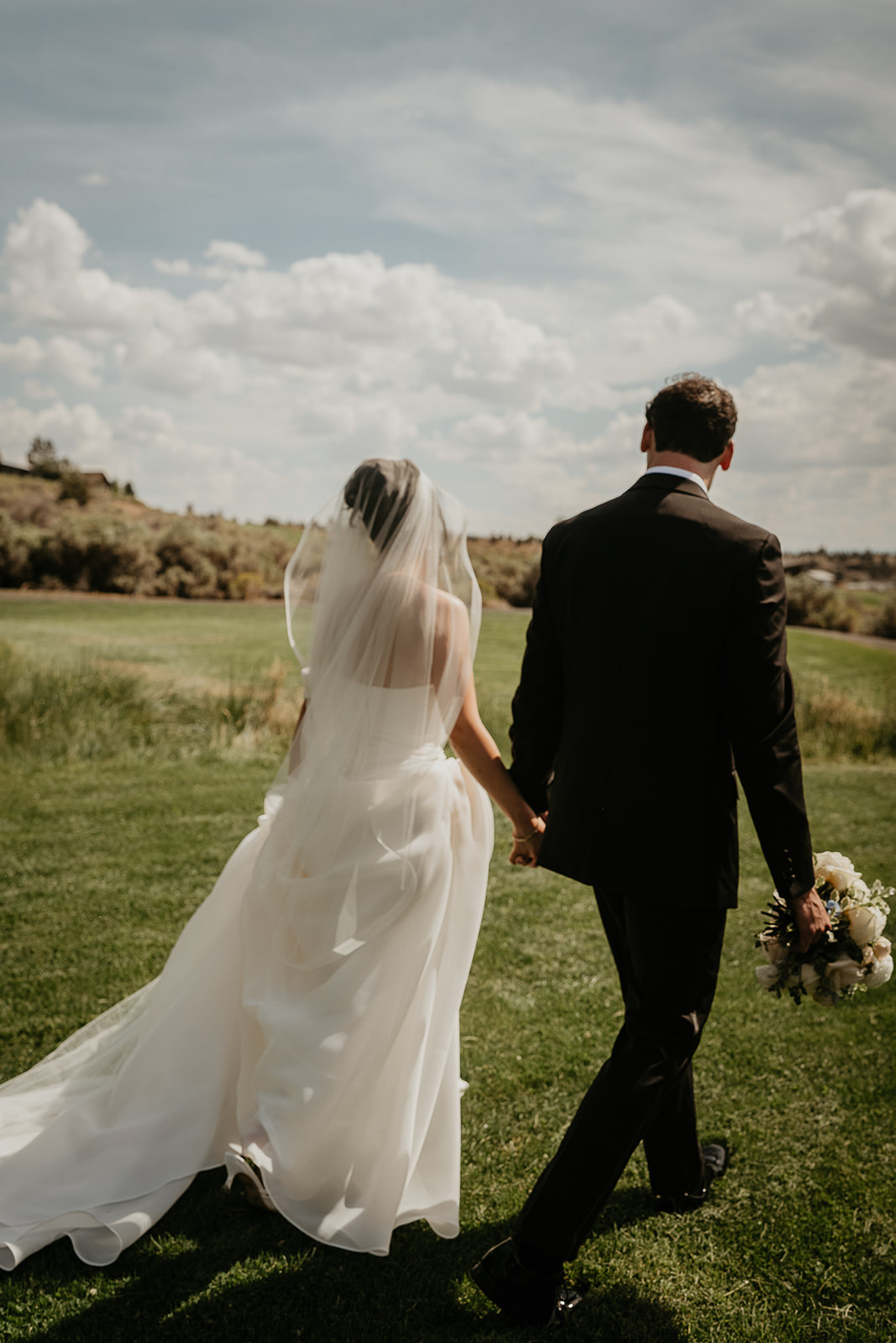 the newlyweds walking onto a grassy lawn holding hands during their Brasada Ranch wedding.