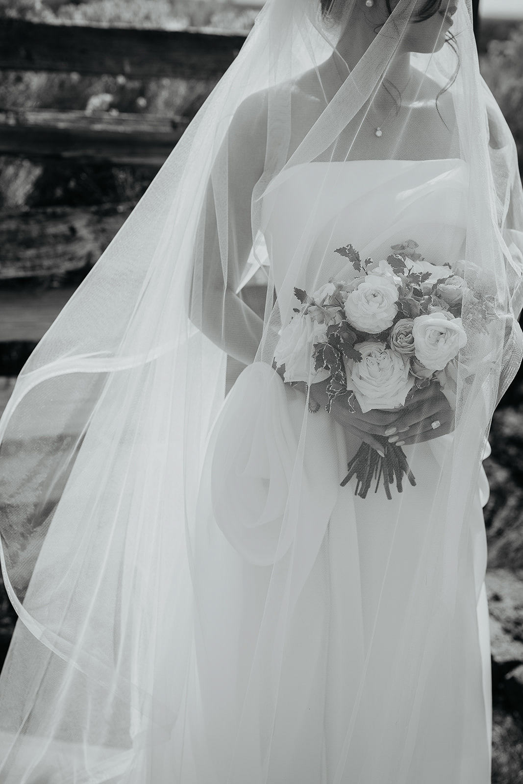 the bride holding a bouquet of flowers as her veil flows in the wind.