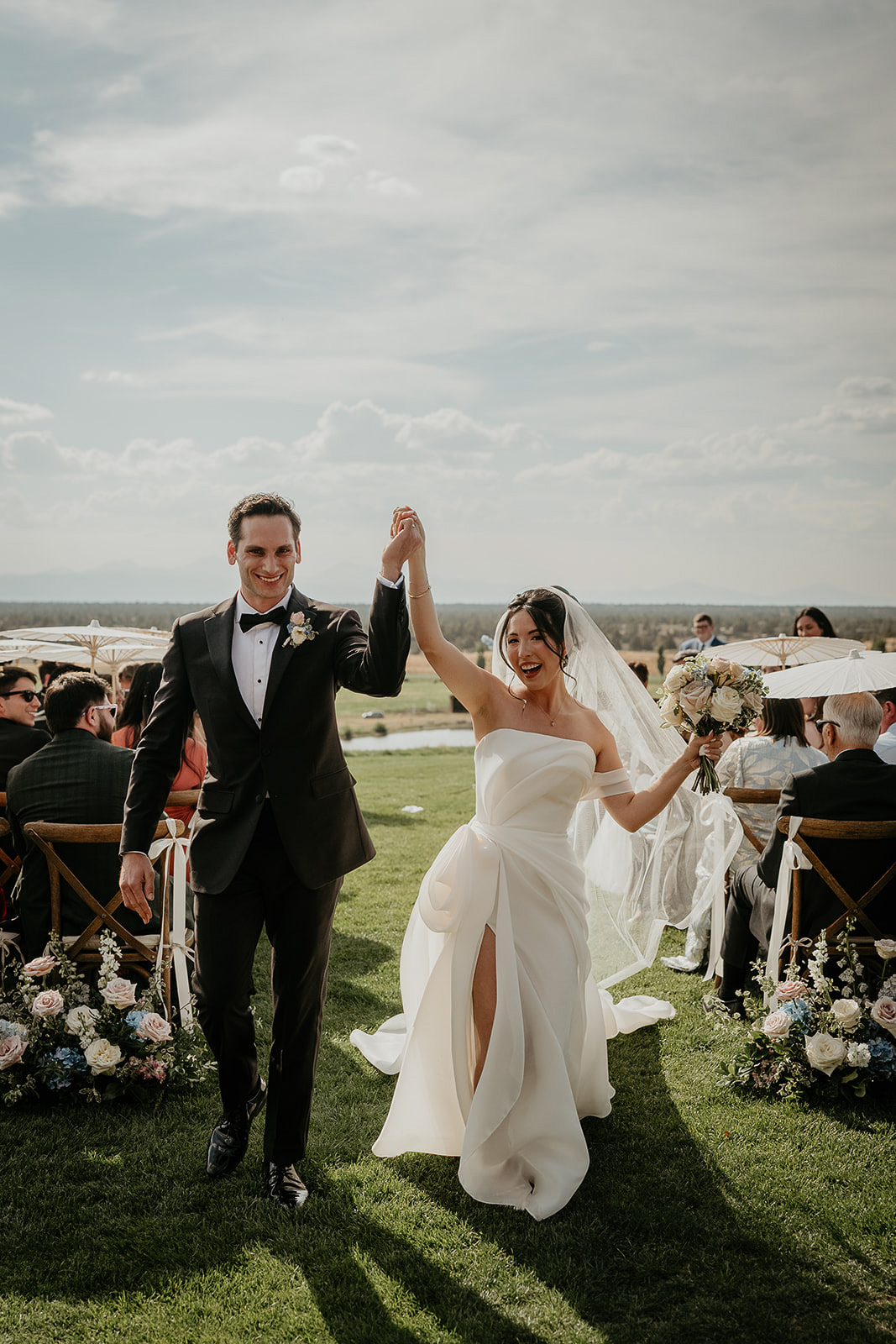 the newlyweds holding hands walking down the aisle during their Brasada Ranch wedding.